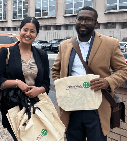 Concentric branded bags held by two people, associated with partnership and outreach efforts