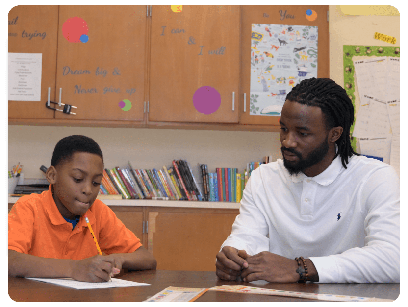 Professional Student Advocate assisting a student with a writing assignment in a classroom setting, providing educational support