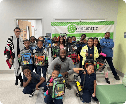 Group photo of children and adults with backpacks, representing community support with Concentric Educational Solutions